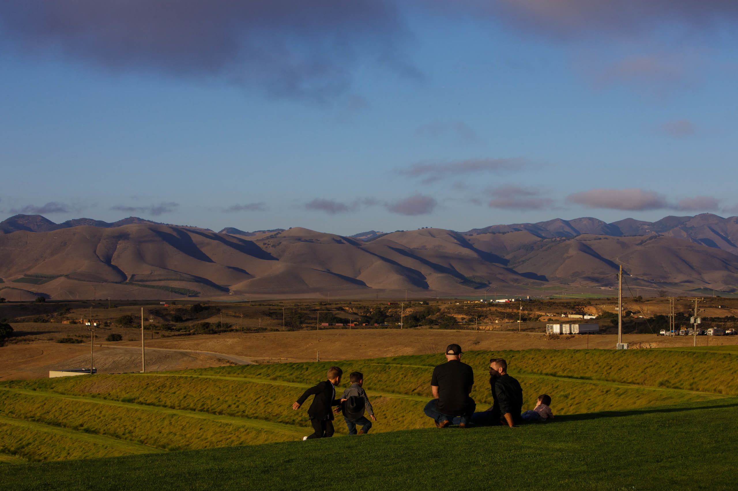 Families sitting on the terraced lawn at C.M.T. Ranch at golden hour, with the Santa Maria hills behind them.
